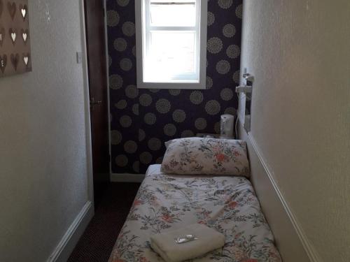 a small room with a bed and a window at Belroy Hotel in Blackpool