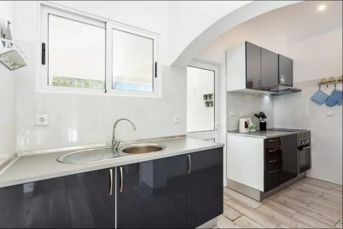 a white kitchen with a sink and a window at Blife Lucelya private rooms at Faro beach in Faro