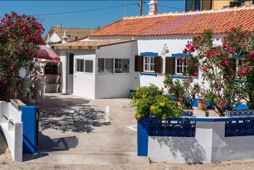 a white house with flowers in front of it at Blife Lucelya private rooms at Faro beach in Faro