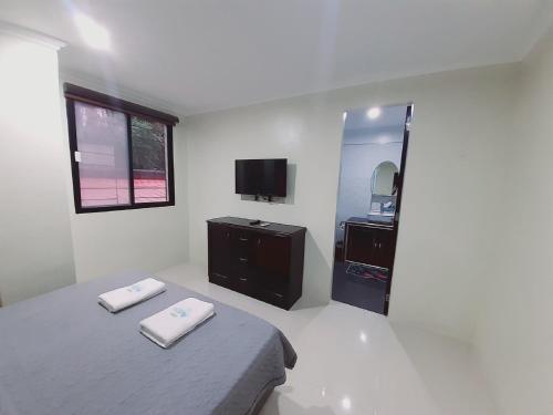 a white bedroom with a bed and a tv at Avana Hills Boracay Prime Horizon Suite 103 in Boracay