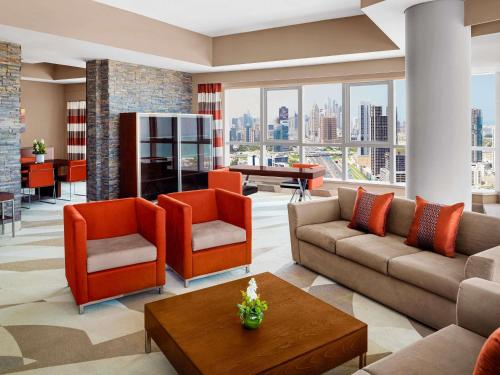 a living room with a couch and chairs and a table at Novotel Dubai Al Barsha in Dubai