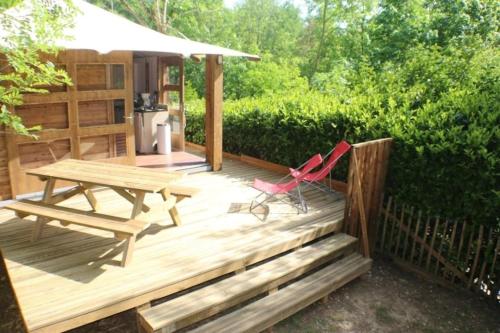 a wooden deck with a picnic table and chairs at ZEcamping 3 étoiles avec piscine bar et restaurant en bord de ruisseau in Belguiral