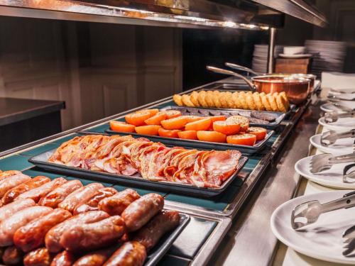 una línea de buffet con diferentes tipos de comida en bandejas en Mercure Exeter Southgate Hotel, en Exeter