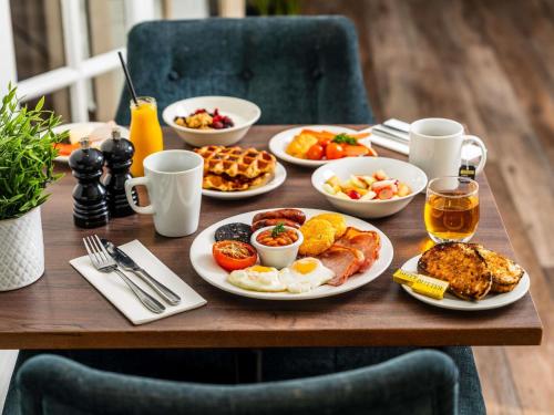 Una mesa de madera con platos de desayuno encima. en Mercure Exeter Southgate Hotel, en Exeter