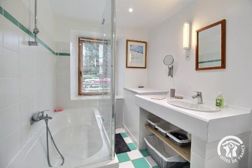 a white bathroom with a tub and a sink at Le havre de kerariou in Trébeurden