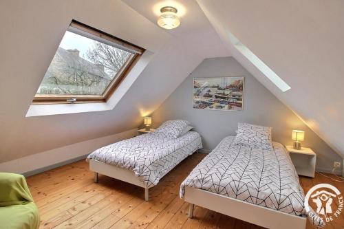 two beds in a attic room with a window at Le havre de kerariou in Trébeurden