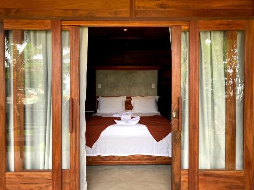 a bedroom with a bed with wooden doors at Villa Caravelas Praia de Moitas in Amontada