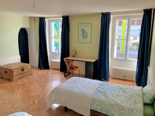 Un dormitorio con cama, escritorio y ventanas en Proche gare et centre-ville, en Chaumont