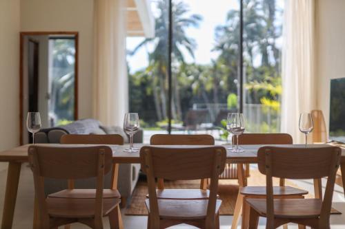 ein Esszimmer mit einem Tisch und Stühlen mit Weingläsern in der Unterkunft Modern Pool Villa Escape in Koh Phangan in Ko Phangan