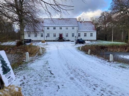 a snow covered road in front of a white building at Lerbæk Hovedgaard in Frederikshavn