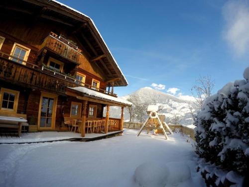 a snow covered house with a playground in front of it at Premium Chalet Zirbe in Emberg