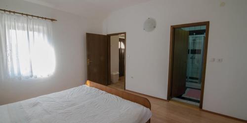 a white bedroom with a bed and a mirror at Flora in Sveti Nicola