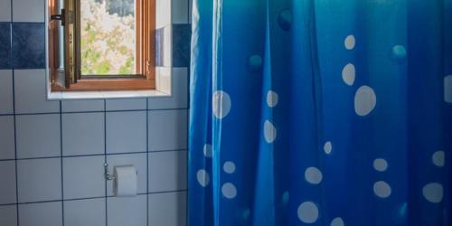 a bathroom with a blue shower curtain and a window at Flora in Sveti Nicola