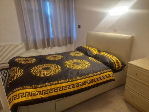 a bedroom with a bed with a black and yellow blanket at Oakfield Gardens NY in Edmonton