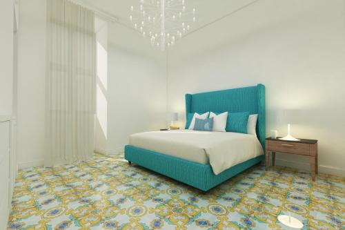 ein Schlafzimmer mit einem blauen Bett und einem Kronleuchter in der Unterkunft Palazzo Gargiulo Luxury Rooms & Suites in Sorrent