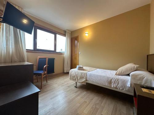 a bedroom with a bed and a chair and a window at Hotel Santa Catalina by Bossh Hotels! in A Coruña