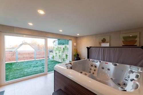 een badkuip in een badkamer met een groot raam bij Dôme du levant in Holving