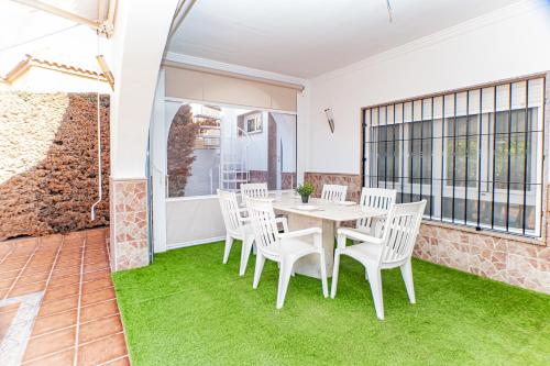 a dining room with white chairs and a table and grass at Villa Daniela in Retamar