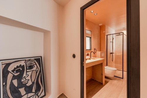 a bathroom with a painting of a woman on the wall at Nobi Boutique Surf Hotel Taghazout in Tamraght Ouzdar
