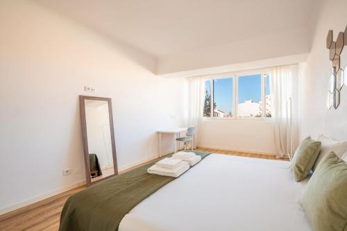 コスタ・ダ・カパリカにあるGuestReady - Cozy Beachside Retreatの白いベッドルーム(大型ベッド1台、鏡付)