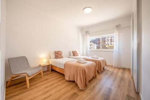 コスタ・ダ・カパリカにあるGuestReady - Cozy Beachside Retreatのベッド2台と椅子と窓のある寝室