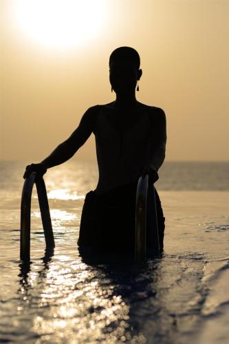 una mujer sentada en el agua en la playa en Radisson Blu Hotel, Conakry, en Conakry