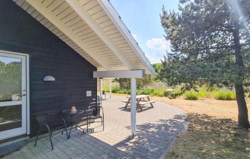 un patio con sedie, un tavolo e una tenda da sole di Nice Home In Løkken a Lyngbytorp
