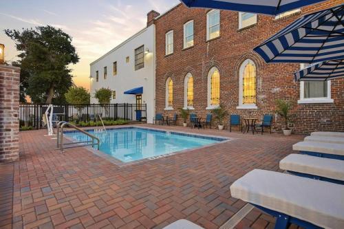 a swimming pool in front of a brick building at The Ray Soulful King Studio Pool in Jacksonville