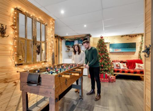 Private beach with SPA on the lake I Plage Sucrée في Saint-Rémi-dʼAmherst: رجل وامرأة يقفان أمام طاولة طاولة كرة قدم