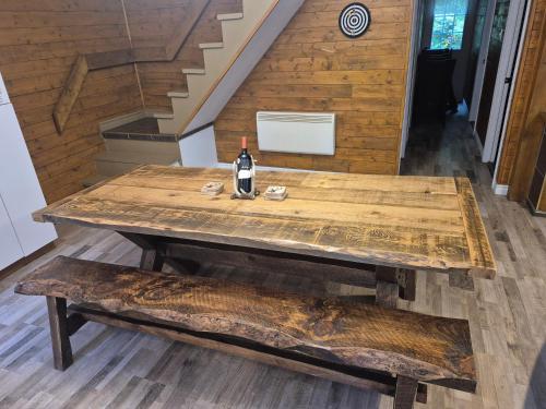 een houten tafel met een fles wijn en een bank bij Chalets du Domaine - RUSTIQUE in Notre-Dame-Des-Bois