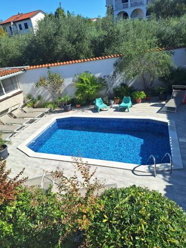 a large swimming pool in a yard with chairs around it at Apartment with private pool and arbor in Malinska