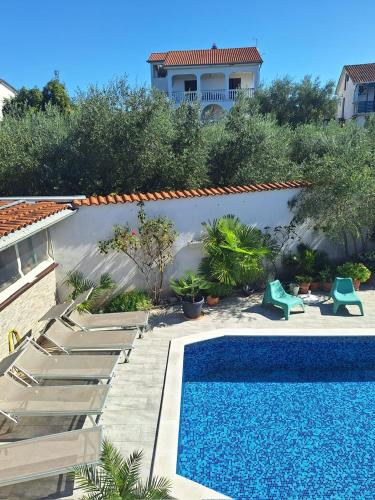 a swimming pool with chairs and a house at Apartment with private pool and arbor in Malinska
