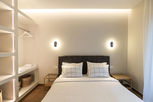 una camera da letto con un letto grande con lenzuola e cuscini bianchi di Likno a Alexandroupoli