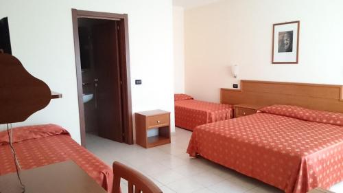 a hotel room with two beds and a table at Hotel Holiday House in San Giovanni Rotondo