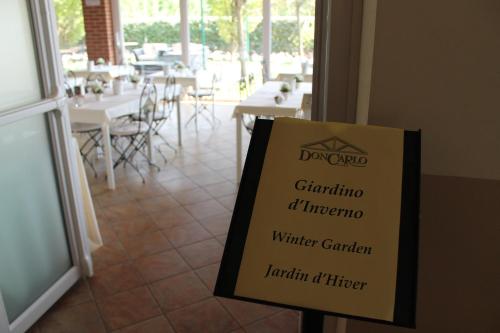 a sign in front of a restaurant with tables and chairs at Hotel Don Carlo in Broni