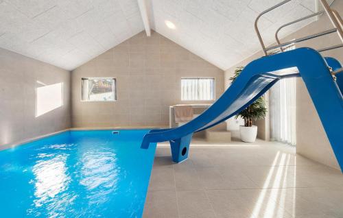 ein Hallenbad mit einer blauen Rutsche in einem Raum in der Unterkunft Cozy Home In Glesborg With Sauna in Fjellerup