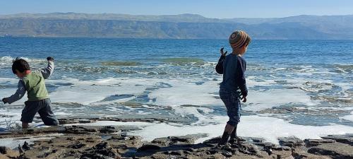twee kinderen spelen op de rotsen in het water bij מול ים המלח in Ovnat