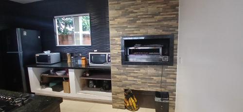 a kitchen with a counter with a microwave and a tv at Sobrado de 3 quartos in Capão da Canoa