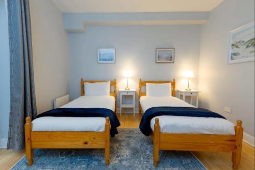 2 camas en una habitación con 2 mesas y 2 lámparas en Tonn Na Mara - Galway Lakeside Apartments, en Galway