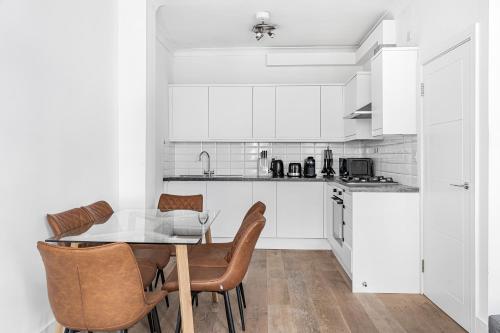 a kitchen with white cabinets and a table and chairs at Chancery Lane Residences in London