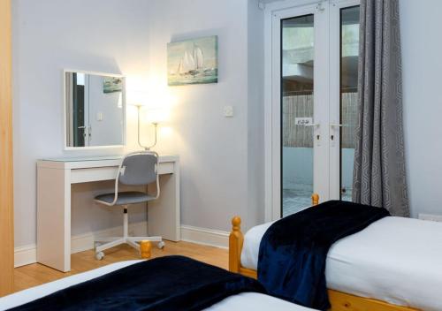 a bedroom with two beds and a desk with a mirror at Tonn Na Mara - Galway Lakeside Apartments in Galway