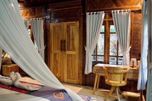 a bedroom with a bed with curtains and a desk at Beehive Cottages in Amed