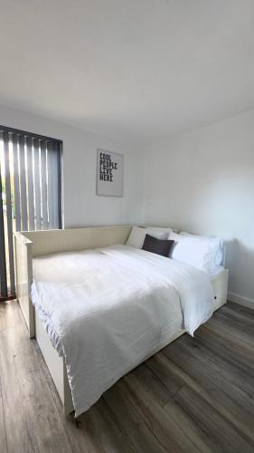 um quarto com uma cama grande com lençóis brancos em Cozy 2-Bedroom Cottage-Style Home em Dublin