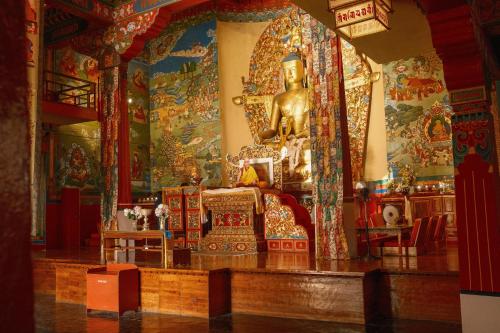 ein Schrein in einem Tempel mit einer großen Goldstatue in der Unterkunft Shepherds Of Dharamshala in Dharamsala