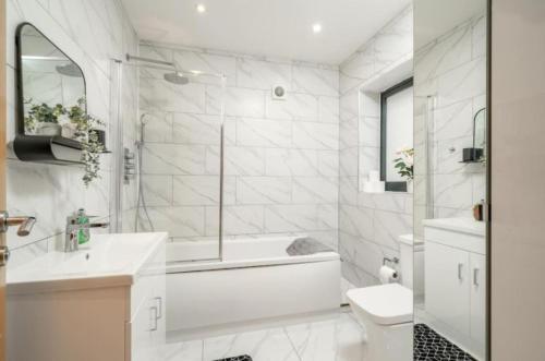 a bathroom with a tub and a toilet and a sink at Large 3BR House by D3 Short Stay, Sleeps 9, Parking & Near to Tottenham Stadium in London