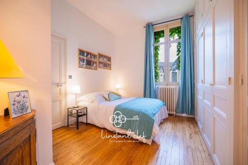 a bedroom with a bed with blue curtains and a window at Escale de charme à Tours - Parking, Patio & Hyper centre in Tours