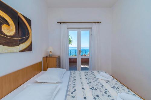a bedroom with a bed and a view of the ocean at Apartments Kunac in Podgora