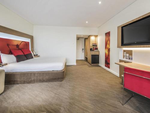 a hotel room with a bed and a flat screen tv at Novotel Sydney West HQ in Rooty Hill