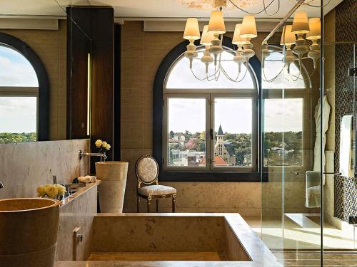 a bathroom with a tub and a chair and windows at Sofitel Montevideo Casino Carrasco & Spa in Montevideo