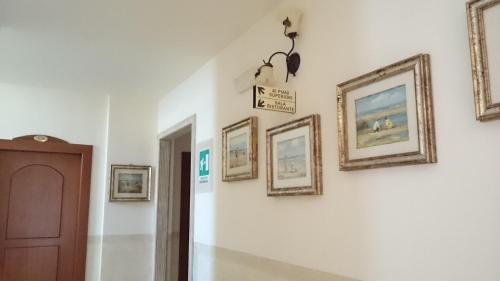 a hallway with framed pictures on a wall at Hotel Holiday House in San Giovanni Rotondo